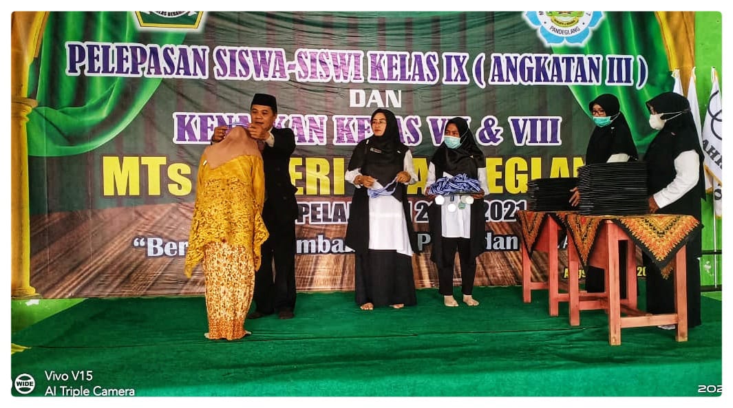 Ade Isma Nurfata, S.Pd. Kepala madrasah MTsN 7 Pandeglang mengalungkan Medali sebagai simbol melepas sisudawan kembali pada orang tuanya.